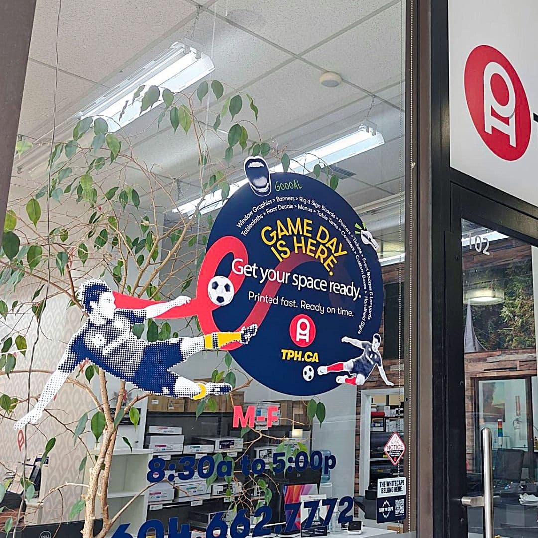 A printing service window display features a large blue circle promoting "Game Day is Here" with soccer player cutouts and "TPH.CA".