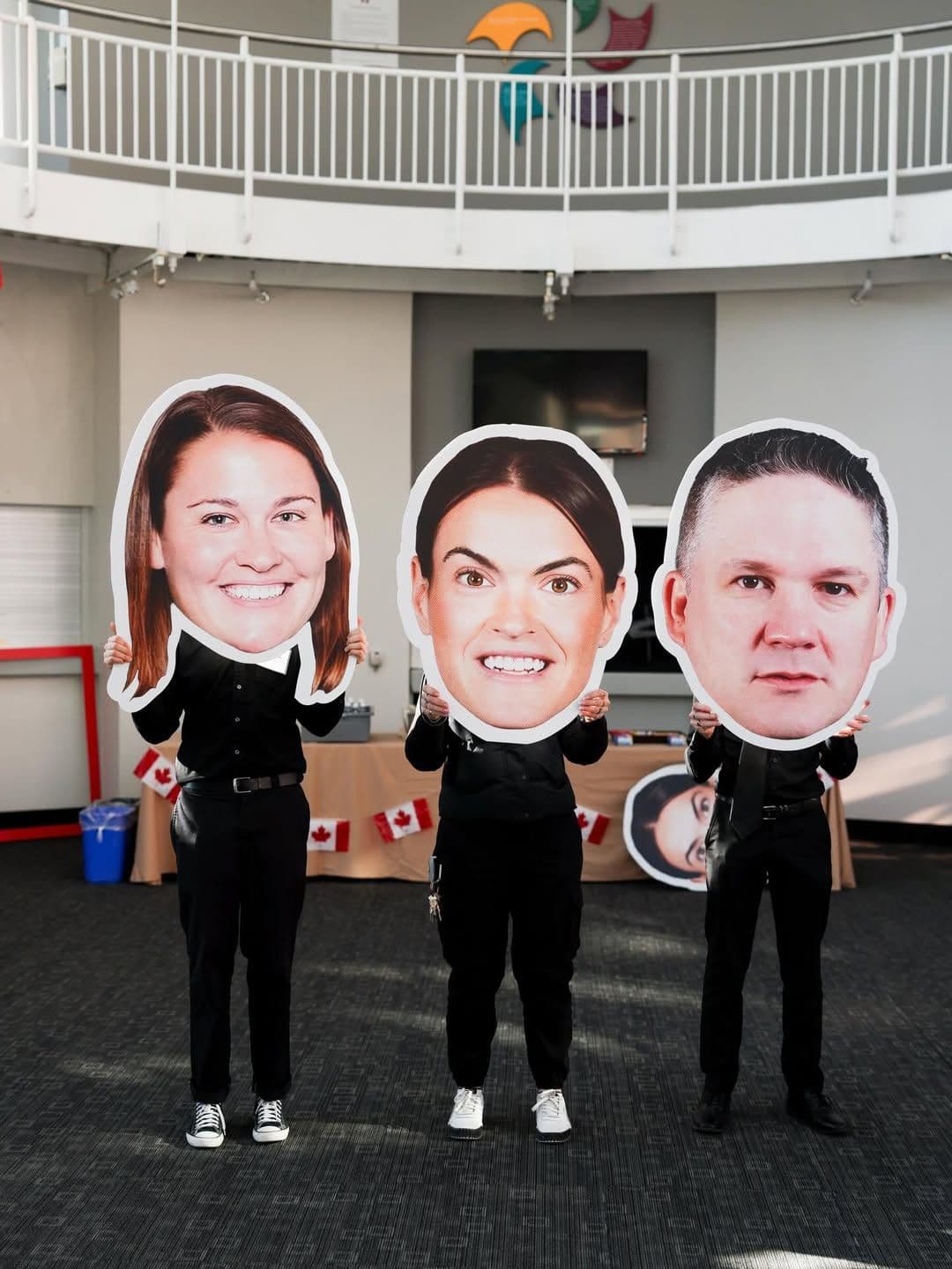 Three people holding oversized printed cutouts of faces during an indoor event, showcasing a custom large‑scale print project by TPH.