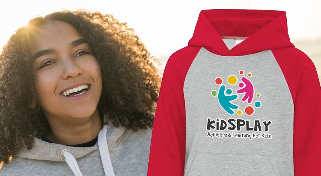 Image of a smiling girl next to a custom hoodie featuring a school logo.